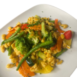 Colorful vegetable stir-fry with broccoli, carrots, green beans, peppers and diced chicken on a white plate. Eierspätzle mit frischem Gemüse